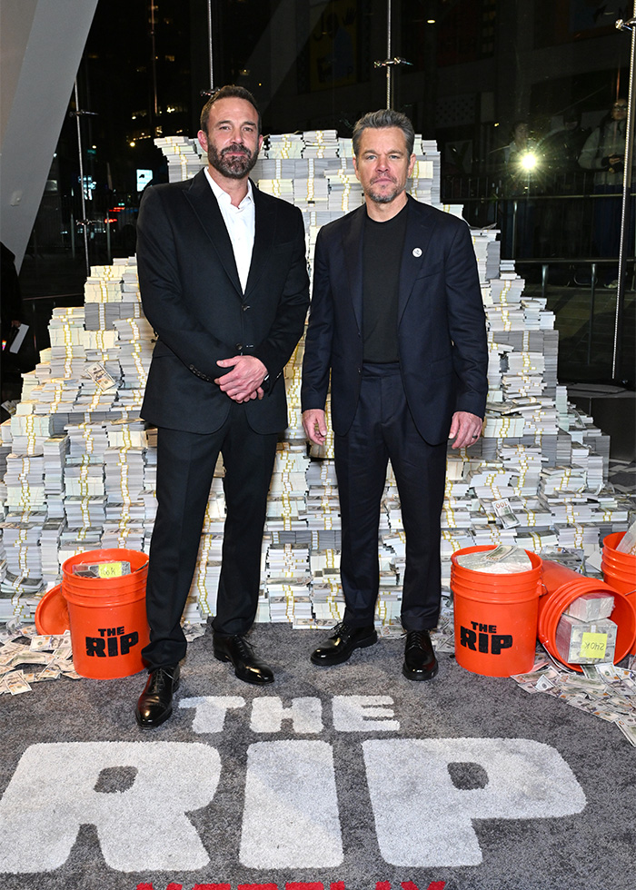 Matt Damon in a sharp black suit striking a red carpet pose at a promotional event for The Rip.