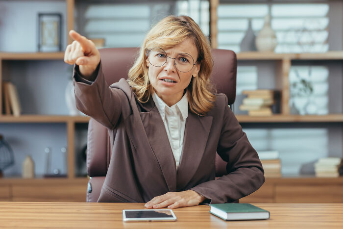 Frustrated woman in office pointing forward, illustrating moments people realized they no longer wanted to work and quit.