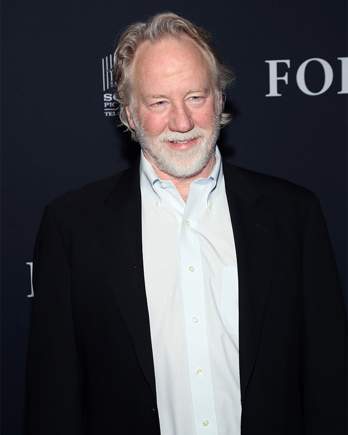 Man with white beard and hair wearing a black blazer and light blue shirt at a formal event about Melissa Gilbert husband Timothy Busfield.