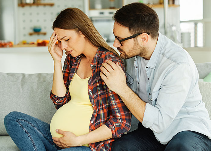 Pregnant woman upset on couch while partner comforts her, highlighting expired food in her pantry from 1999 issue. Pregnant woman upset on couch while partner comforts her, highlighting expired food in her pantry from 1999 issue.
