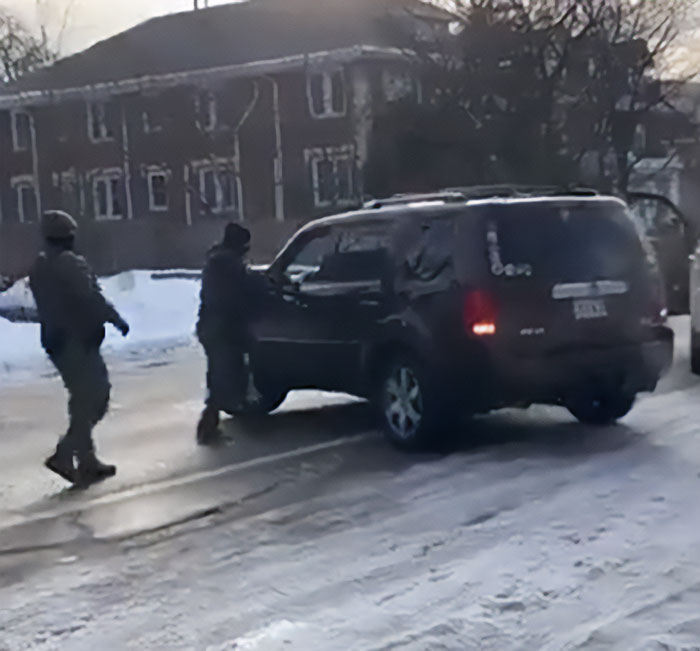 Two armed men approaching a dark SUV on a snowy street, related to father of ICE agent amid immigrant wife bombshell.
