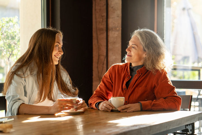 Two women enjoying coffee together indoors, highlighting a sister taking their mom out for dinner on her birthday. Two women enjoying coffee together indoors, highlighting a sister taking their mom out for dinner on her birthday.