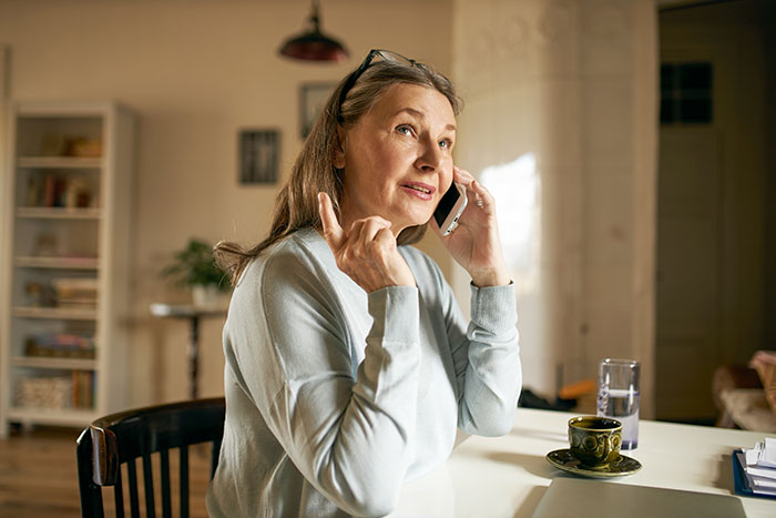 Older religious woman making a phone call at home, expressing emotion related to guilt trips and family conflict. Older religious woman making a phone call at home, expressing emotion related to guilt trips and family conflict.