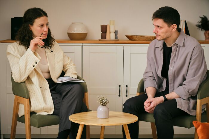 Mom upset husband in a serious conversation, sitting opposite each other in a modern living room setting discussing secret funds. Mom upset husband in a serious conversation, sitting opposite each other in a modern living room setting discussing secret funds.