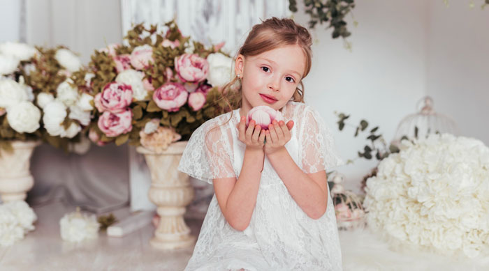 Young girl in white dress at wedding surrounded by flowers, highlighting bride-to-be and unruly kids conflict.