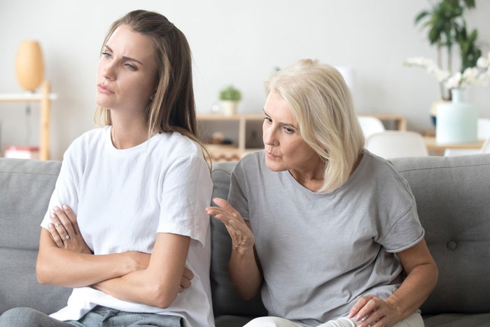 Mom and bride-to-be having a tense conversation about including sister’s unruly kids at the wedding in a living room setting. Mom and bride-to-be having a tense conversation about including sister’s unruly kids at the wedding in a living room setting.
