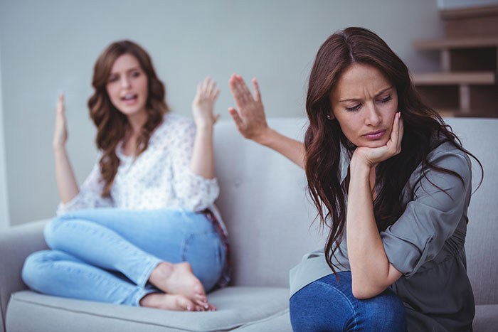 Two women on a couch in a tense conversation, illustrating conflict around woman stealing 5-year-old niece&rsquo;s skirt.