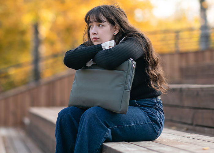 Teenage girl sitting alone on wooden steps in autumn, looking thoughtful and upset amid family divorce conflict. Teenage girl sitting alone on wooden steps in autumn, looking thoughtful and upset amid family divorce conflict.