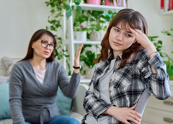 Mother blaming daughter for picking dad in divorce, both sitting indoors with tense expressions during a serious conversation. Mother blaming daughter for picking dad in divorce, both sitting indoors with tense expressions during a serious conversation.