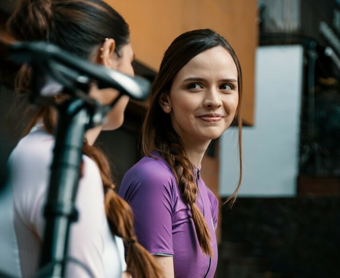 Two women talking outdoors near a bicycle, illustrating things women do to feel safer while living alone. Two women talking outdoors near a bicycle, illustrating things women do to feel safer while living alone.