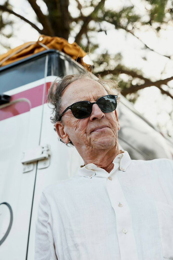 Elderly man wearing sunglasses and a white shirt standing outdoors, reflecting on surprising DNA test results and plot twists.