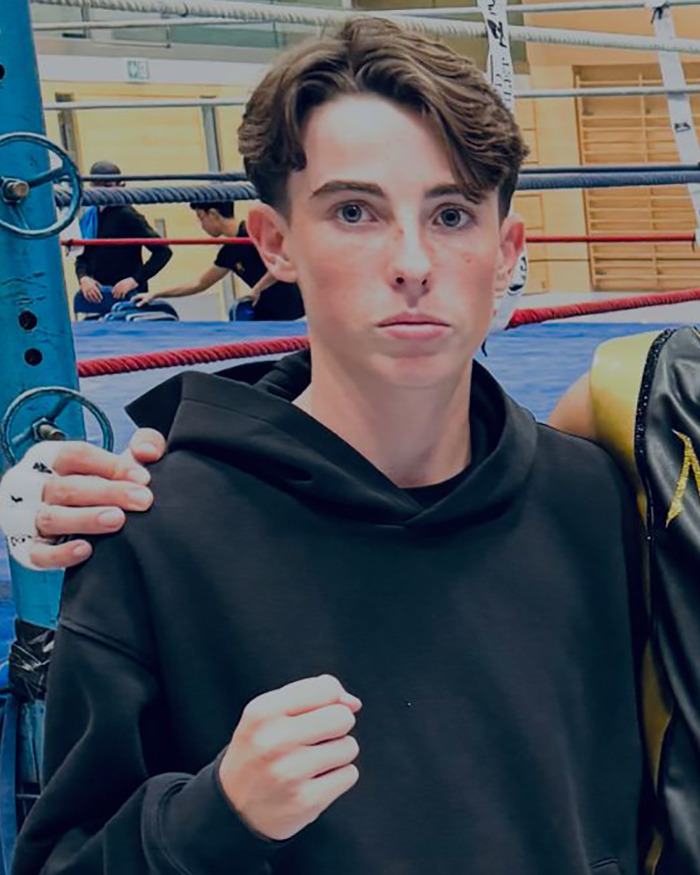 Teenager in a black hoodie with a clenched fist in a boxing ring background, linked to Swiss resort blaze news. Teenager in a black hoodie with a clenched fist in a boxing ring background, linked to Swiss resort blaze news.