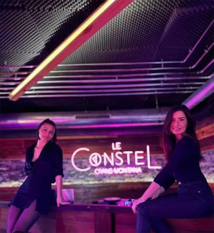 Two women posing inside the Swiss ski bar with purple lighting, related to the cause of the lethal fire negligence investigation. Two women posing inside the Swiss ski bar with purple lighting, related to the cause of the lethal fire negligence investigation.
