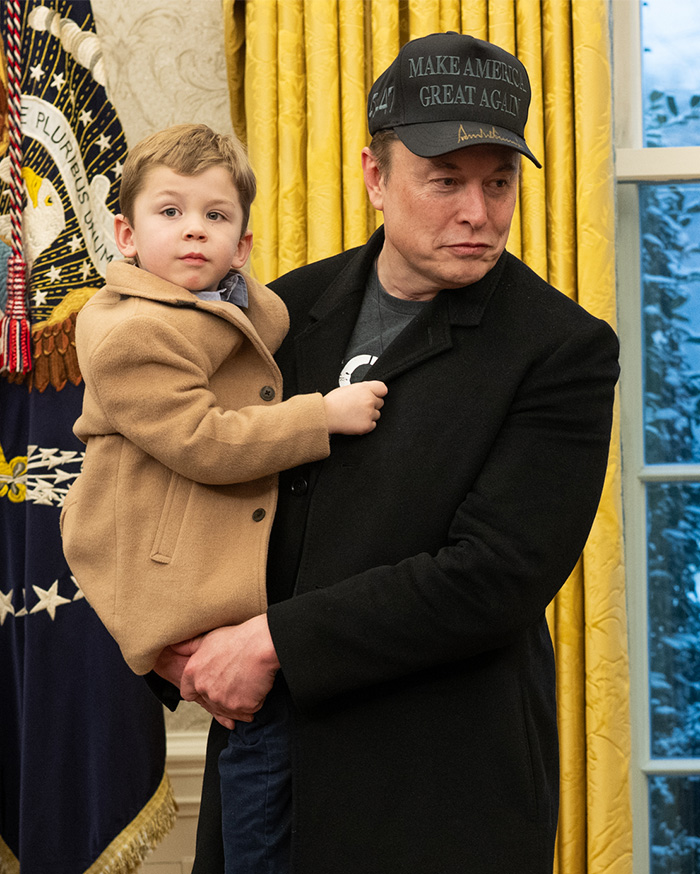 Man holding a child indoors, unrelated to Nicole Richie or her 18‑year‑old daughter&rsquo;s new name reveal.