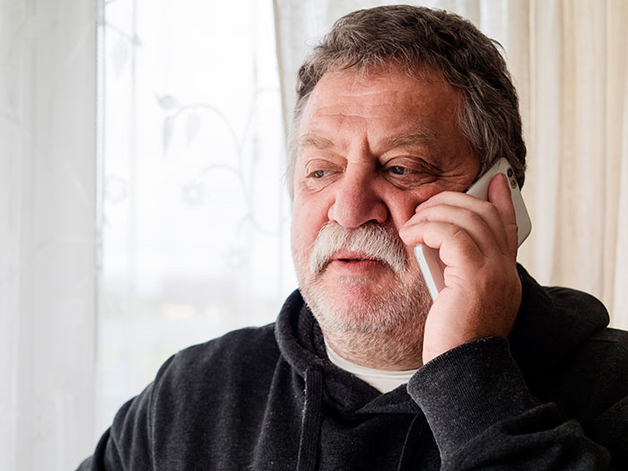 Older man with mustache speaking on phone indoors, illustrating entitled uncle expecting niece to support his retirement plan. Older man with mustache speaking on phone indoors, illustrating entitled uncle expecting niece to support his retirement plan.