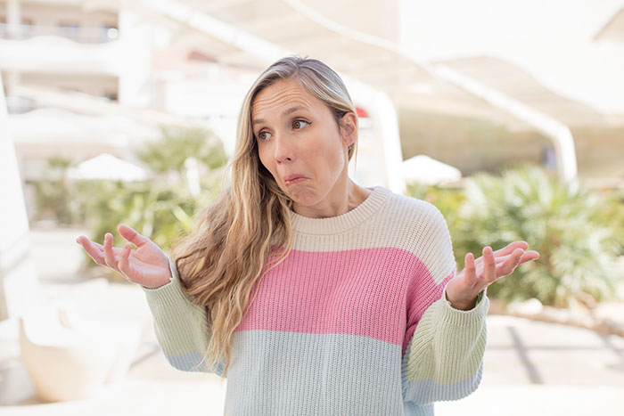 Woman shrugging with a confused expression, illustrating entitled uncle expecting niece to be his retirement plan concept.
