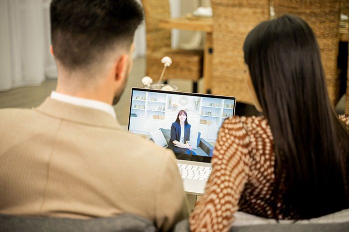 Couple attending an online therapy session on a laptop, discussing paternity test concerns for their young son.