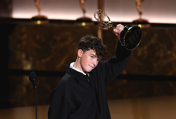 Young celebrity holding up an award on stage, illustrating strict rules celebrities follow during award shows.