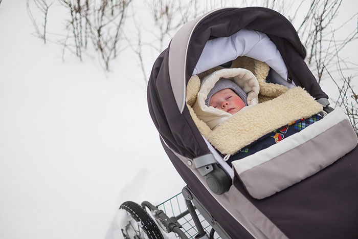Baby bundled in winter clothes inside a stroller, illustrating parenting differences around the world during cold weather.
