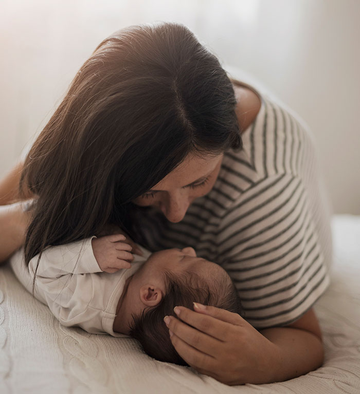 Mother gently cradling and looking lovingly at her newborn baby, highlighting parenting differences around the world.