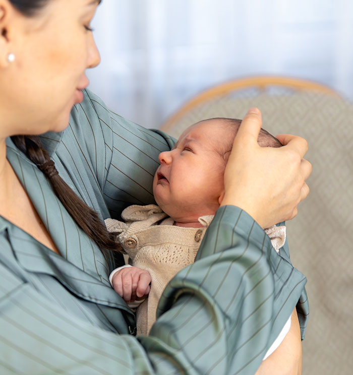 Mother gently comforting her newborn baby, illustrating parenting differences around the world with close care and affection.