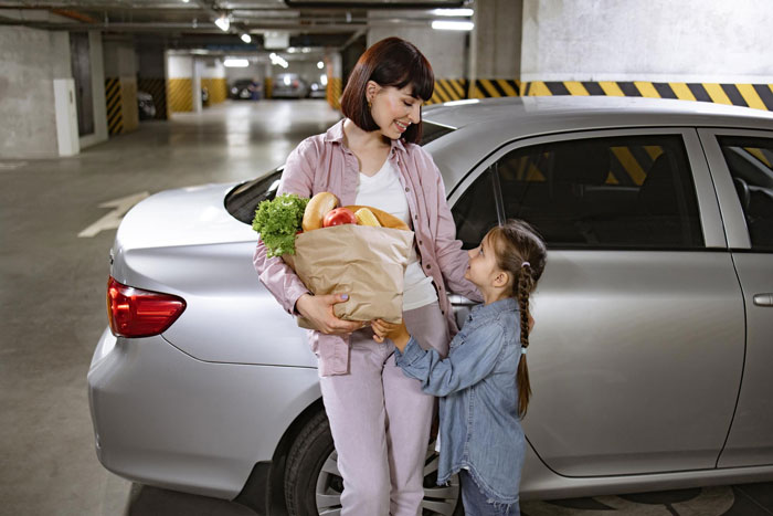 New neighbor eyes and hijacks person's parking place in a residential garage with a silver car nearby.