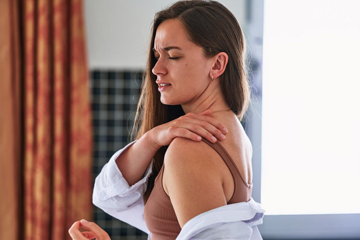 Woman holding her shoulder in pain at home, illustrating partner sleep called ambulance myself situation. Woman holding her shoulder in pain at home, illustrating partner sleep called ambulance myself situation.