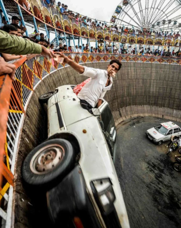 Man performing a car stunt in a crowded arena, a photo shared from a country that hits hard in culture and tradition.
