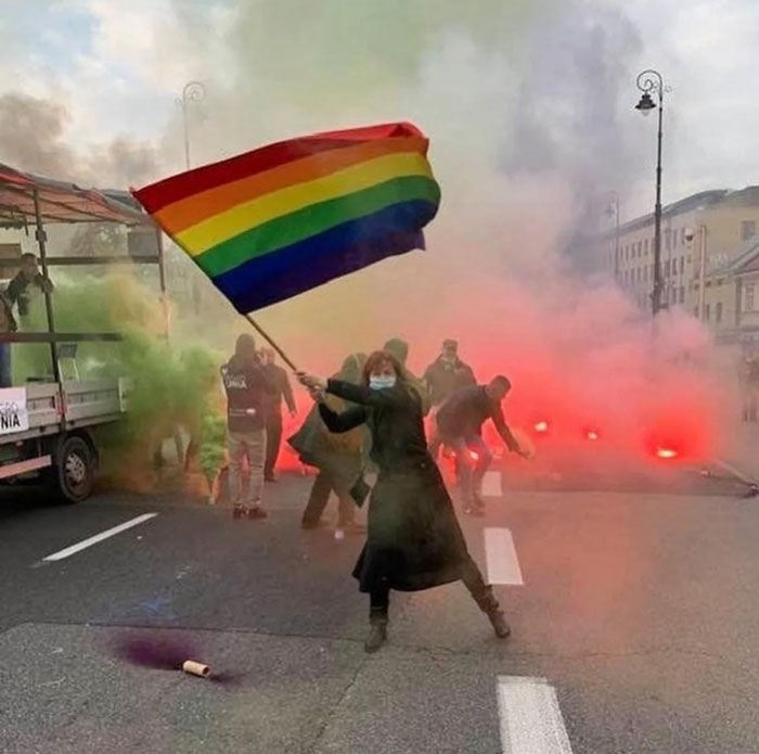Person waving a rainbow flag amid smoke during a protest, capturing a powerful photo shared from their country that hits hard.