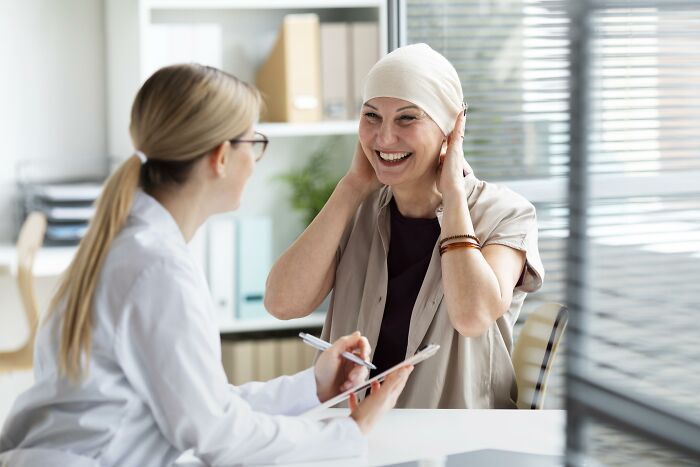 A smiling woman sharing a story with a doctor in a bright office, illustrating people stories about the worst person met.