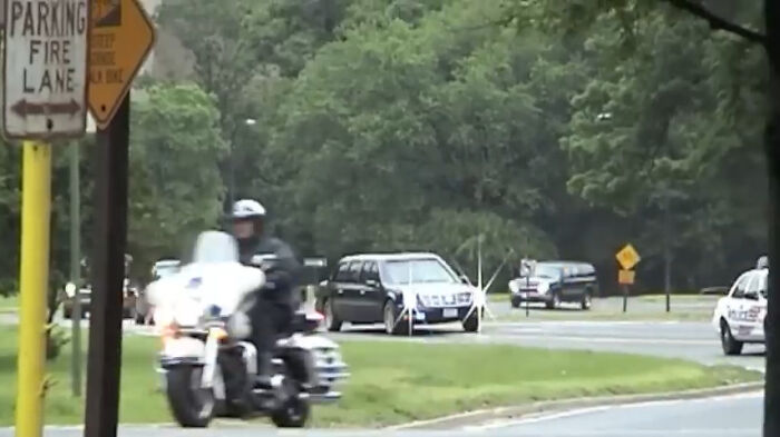 Police motorcycle escort and black hearse on tree-lined road, moments people faced and found unbelievable