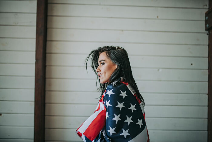 Woman wrapped in an American flag, contemplative portrait evoking moments people faced that felt unbelievable