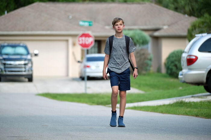 Moments People Faced: teenage boy walks on quiet suburban street with backpack and stop sign in background