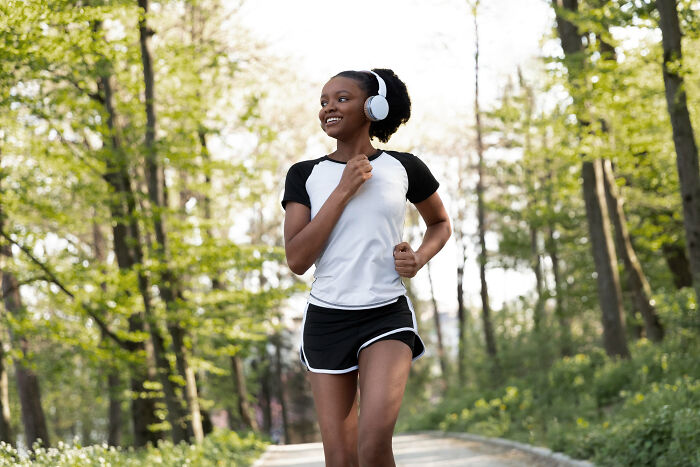Young woman jogging outdoors wearing headphones, representing transformation and stories of folks who morphed unexpectedly.