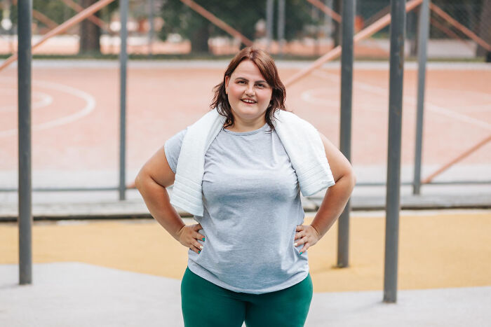 Plus-size woman standing confidently on basketball court after workout, illustrating stories of folks who morphed.