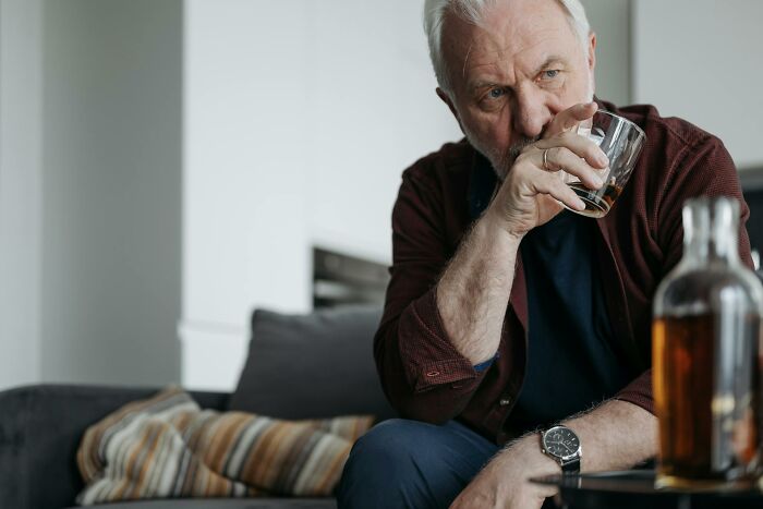 Older man drinking whiskey at home, reflecting deeply in a moment of personal transformation and unexpected change.
