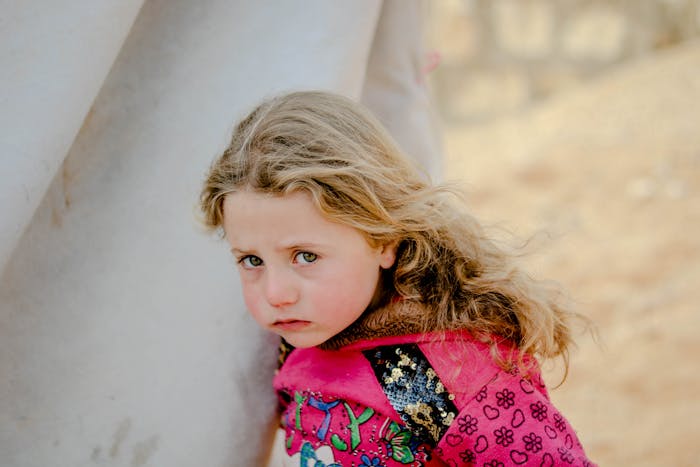 Sad young girl leaning against a wall, reflecting the dad feels guilty for distancing himself from daughter theme.