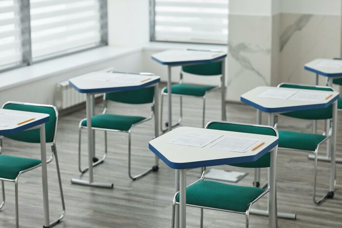 Empty classroom desks with pencils and test papers set up for a hard ACT exam practice session. Empty classroom desks with pencils and test papers set up for a hard ACT exam practice session.