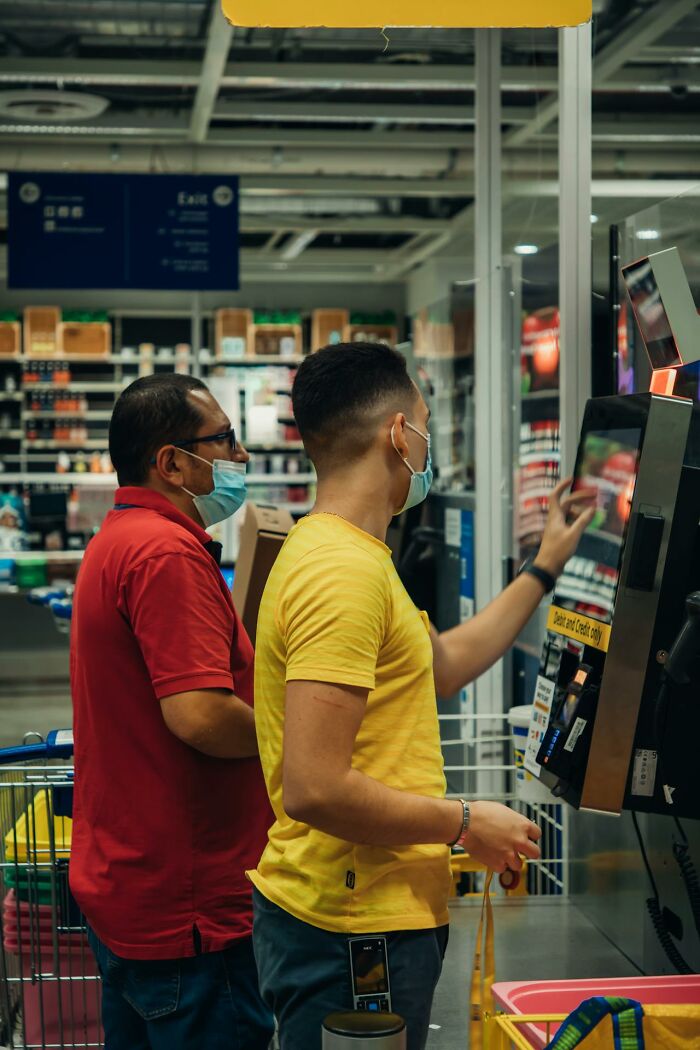 Two men wearing masks interacting with a self-checkout machine, highlighting shocks after they got out of prison.