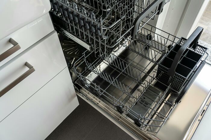 Empty modern dishwasher installed in a kitchen, illustrating everyday home appliances and rich lifestyle contrasts.