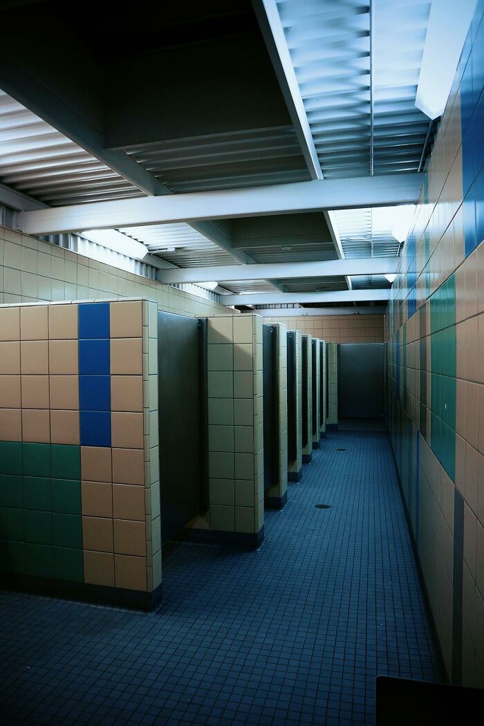 Empty tiled restroom stalls with dim lighting capturing the chaos of a night shift workplace environment.
