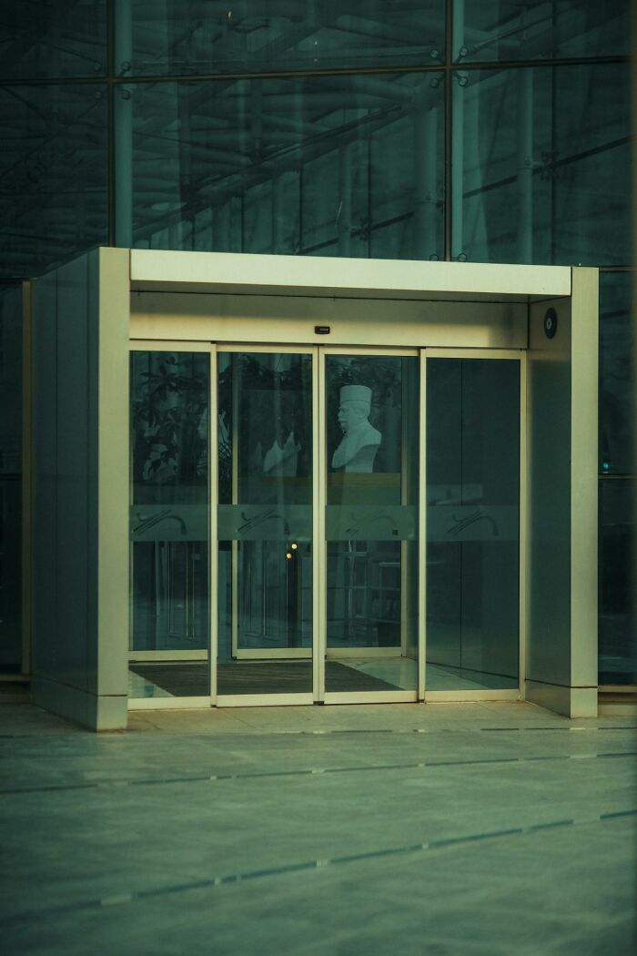 Glass revolving door entrance of a modern building reflecting themes of shock and change after getting out of prison.