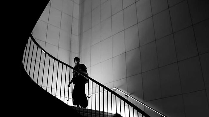 Silhouette of a person walking up a curved staircase in a black and white image, highlighting guessing items in black and white. Silhouette of a person walking up a curved staircase in a black and white image, highlighting guessing items in black and white.