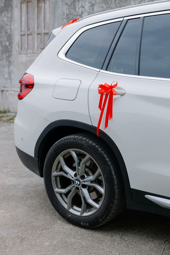 White luxury SUV adorned with red ribbons, symbolizing extravagant gifts linked to rich people’s out of pocket statements.