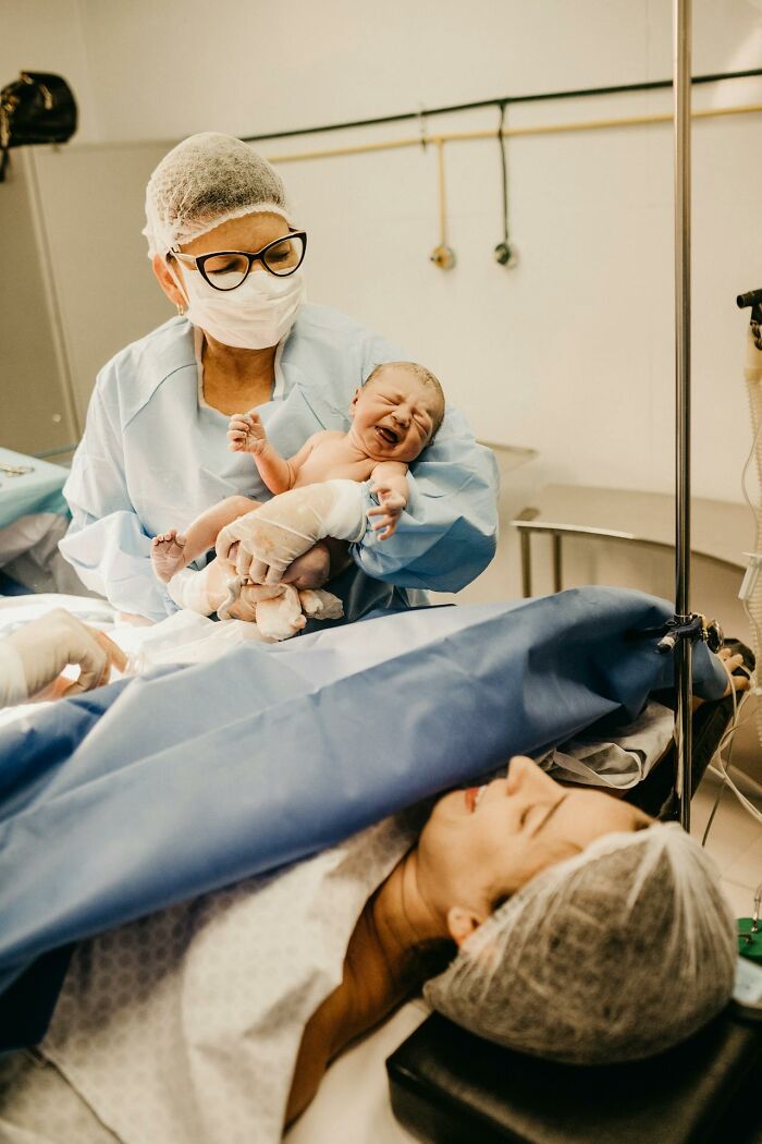 Doctor holding newborn baby after delivery in operating room, illustrating unexplainable medical events and miracles.