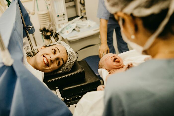 New mother smiling at newborn baby moments after birth in hospital, capturing a special family secrets moment.