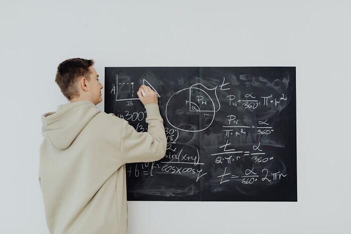 Young man writes complex equations on blackboard, illustrating creepiest displays of intelligence