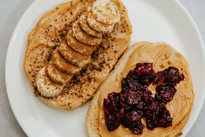 Two slices of bread with peanut butter topped with banana and cinnamon on one, and jelly on the other, showcasing food facts.