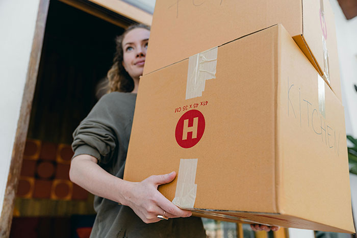 Woman holding moving boxes, symbolizing decades of relocating for husband's career and refusal to move again. Woman holding moving boxes, symbolizing decades of relocating for husband's career and refusal to move again.