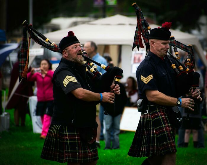 Two men in traditional Scottish kilts playing bagpipes outdoors, highlighting lesser-known facts about these countries.